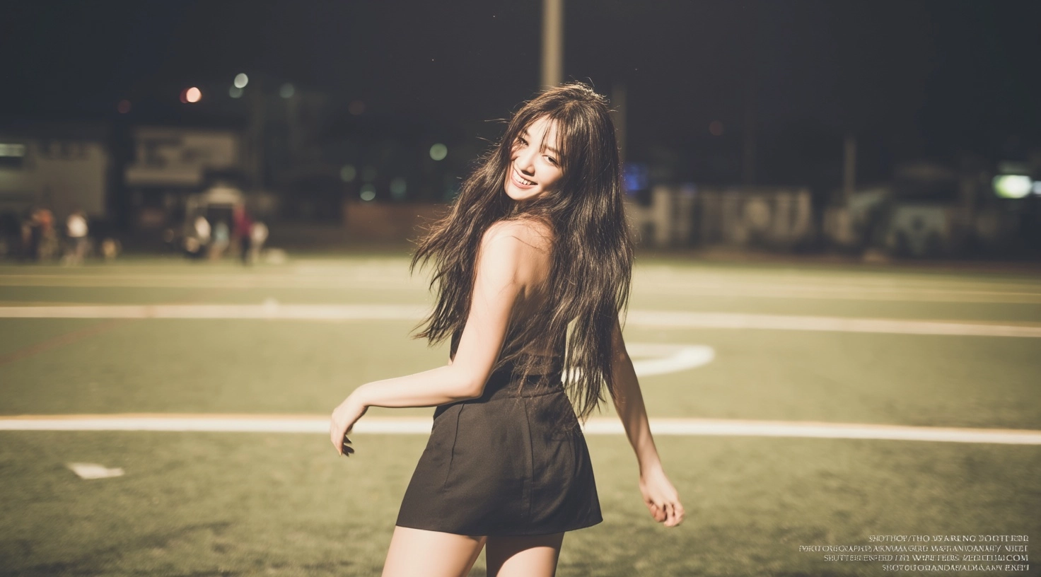 A photo of an asian woman in short skirt, smiling and dancing on the football field at night. she ha