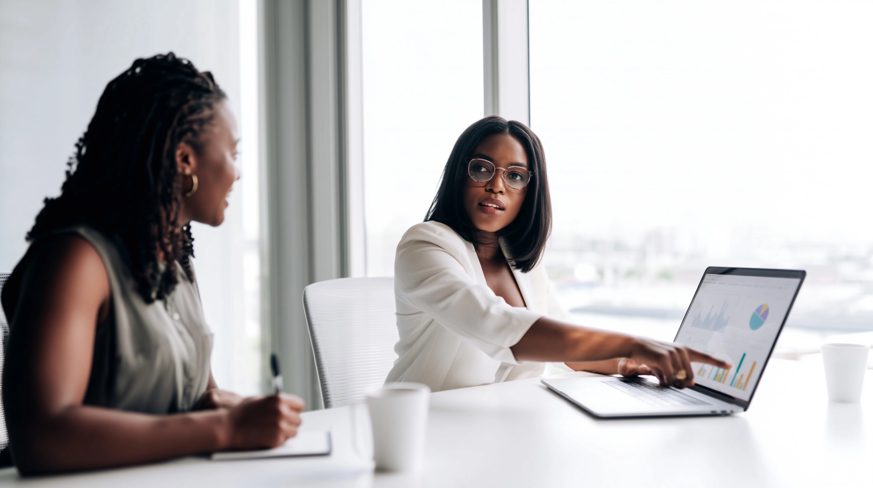 Two white professionals sitting at a clean white desk in a modern office