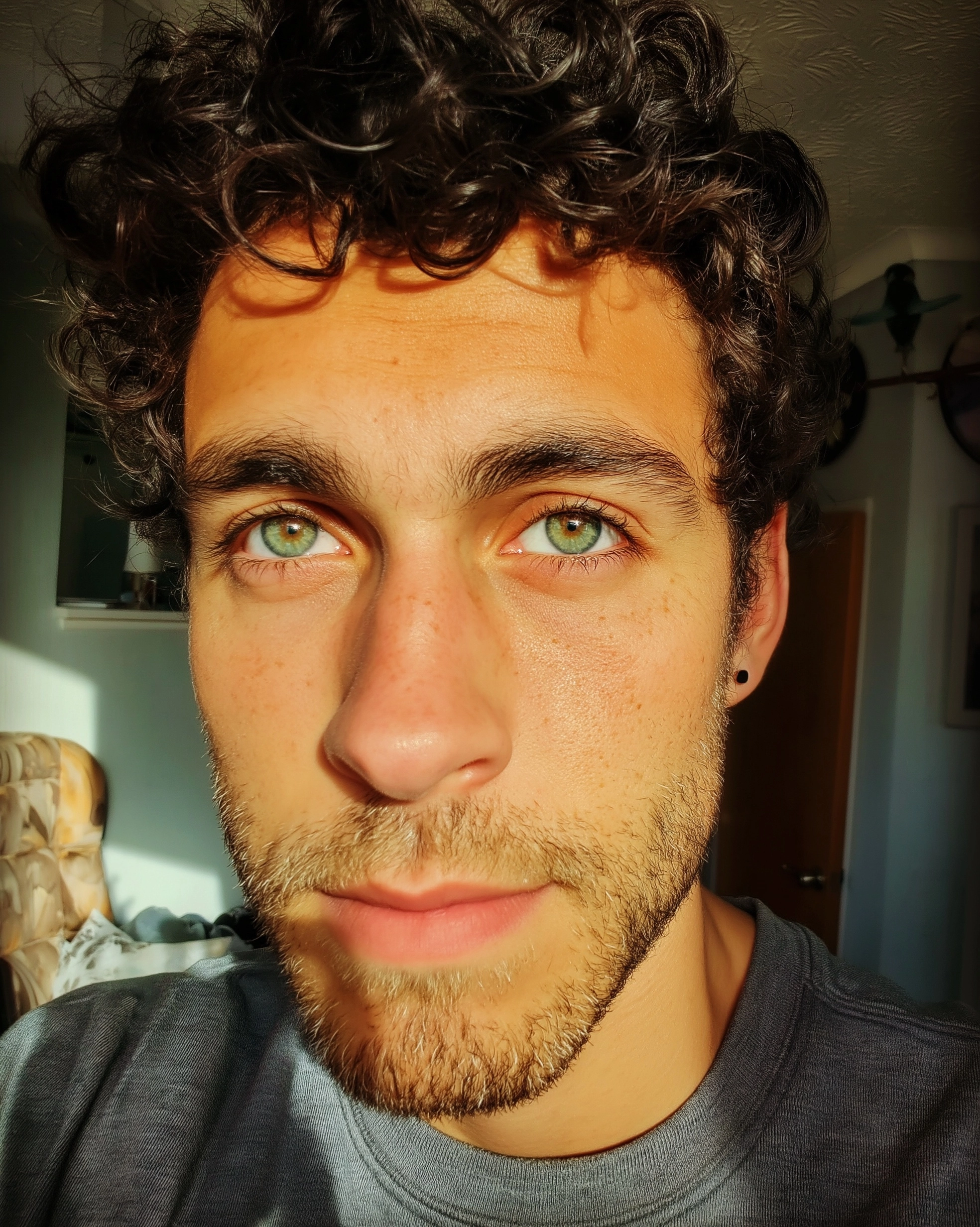 A photograph of an attractive mixed-race man, green eyes, and a stubble beard