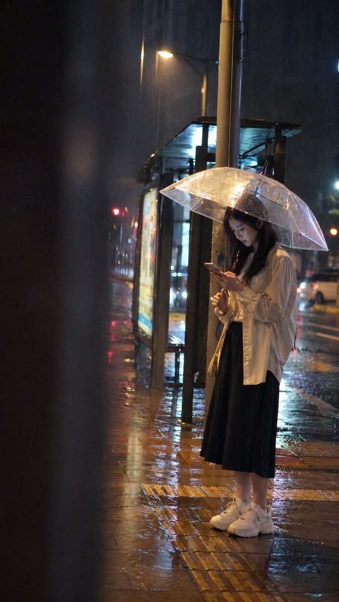Girl Waiting at a Bus Stop on a Rainy Night