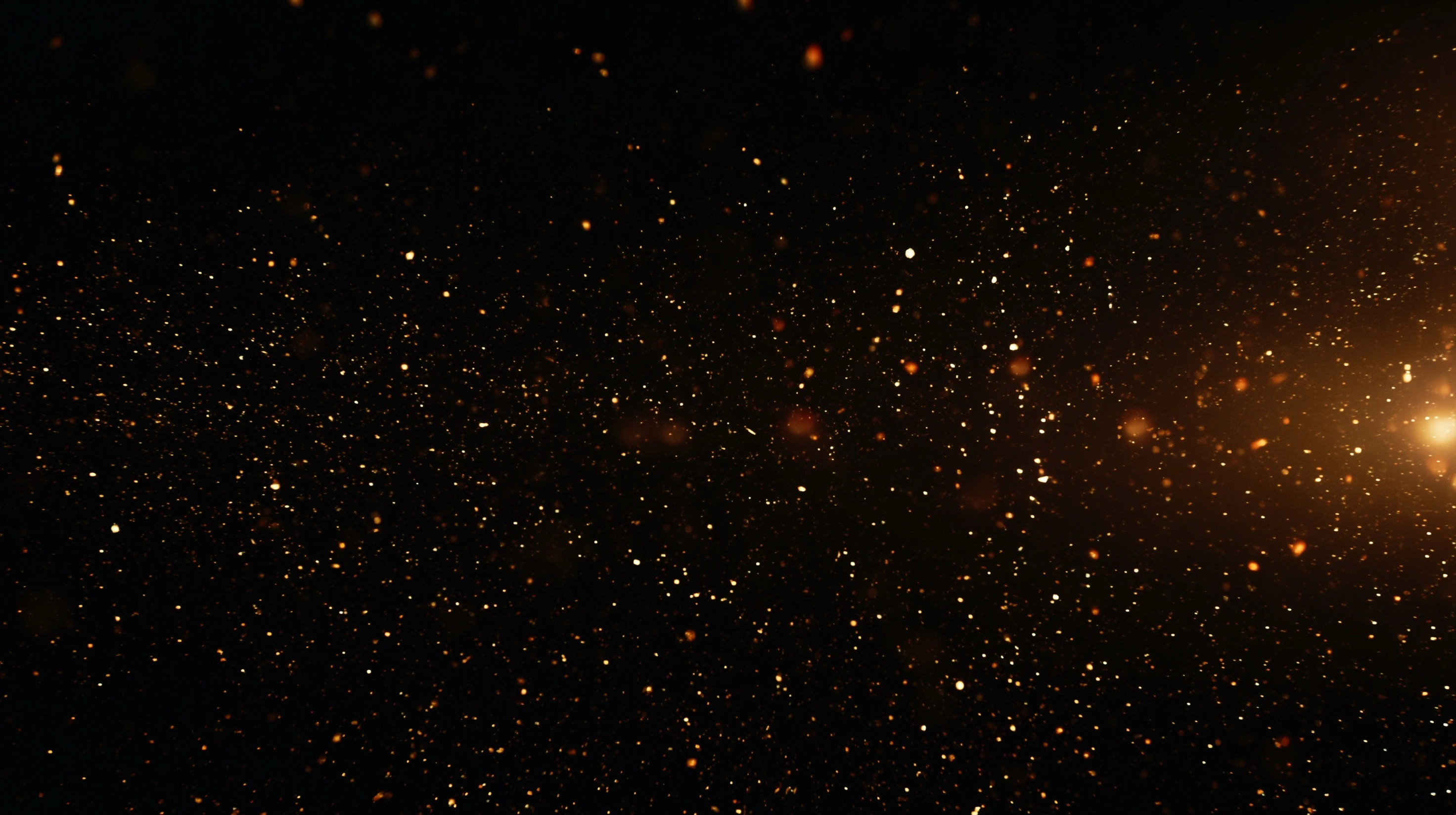 A completely dark black background. Thousands of tiny golden light particles scattered randomly acro