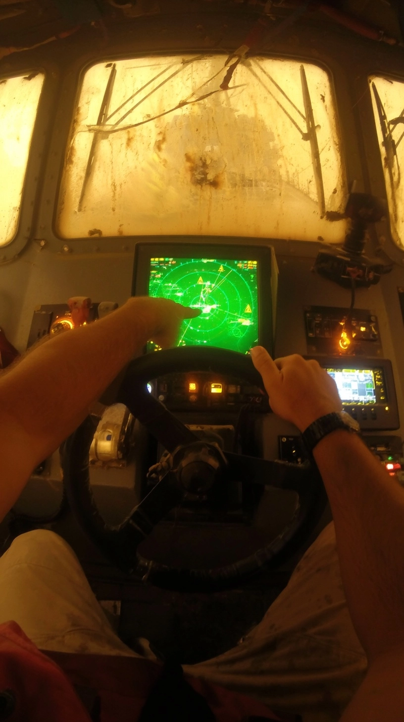Raw GoPro POV hunched inside enclosed patrol boat bridge during blinding sandstorm: your two arms de