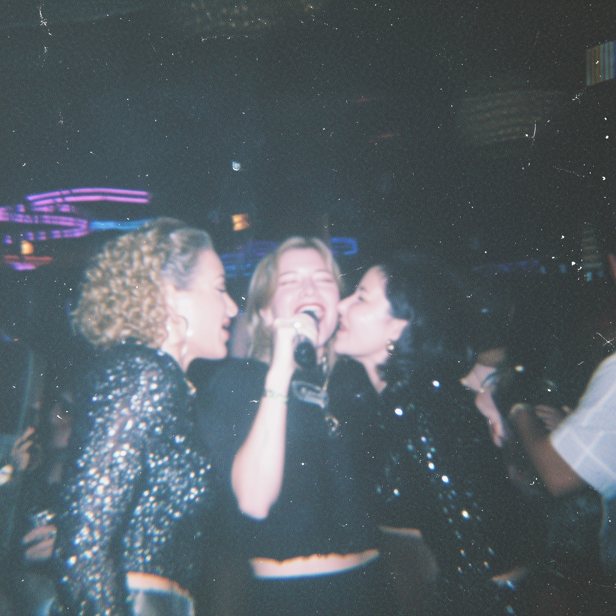 Documentary style nightlife photo of a group of female friends in their 30's singing together in a m