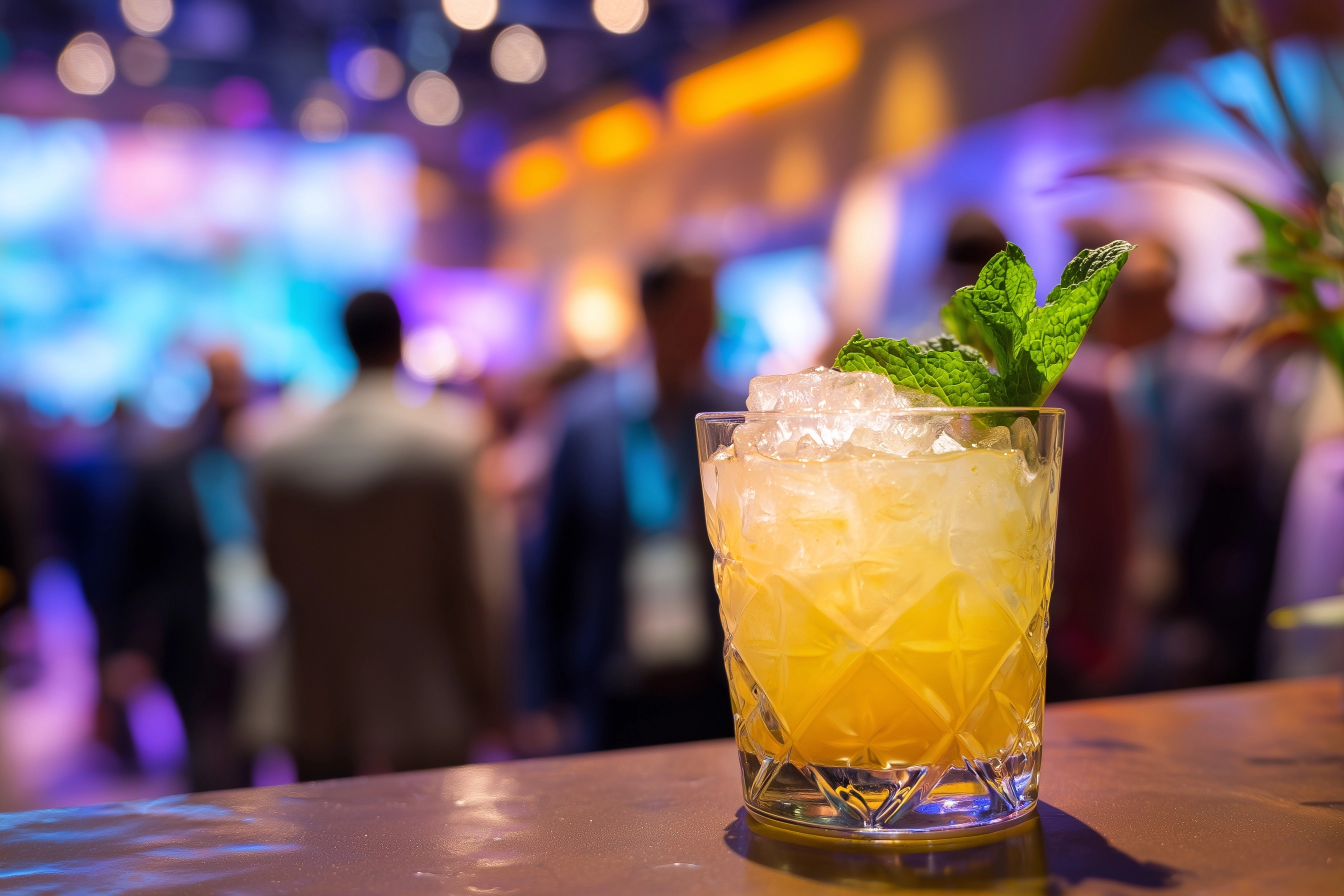 Image of a Mai Tai Cocktail with a corporate event out of focus in the background