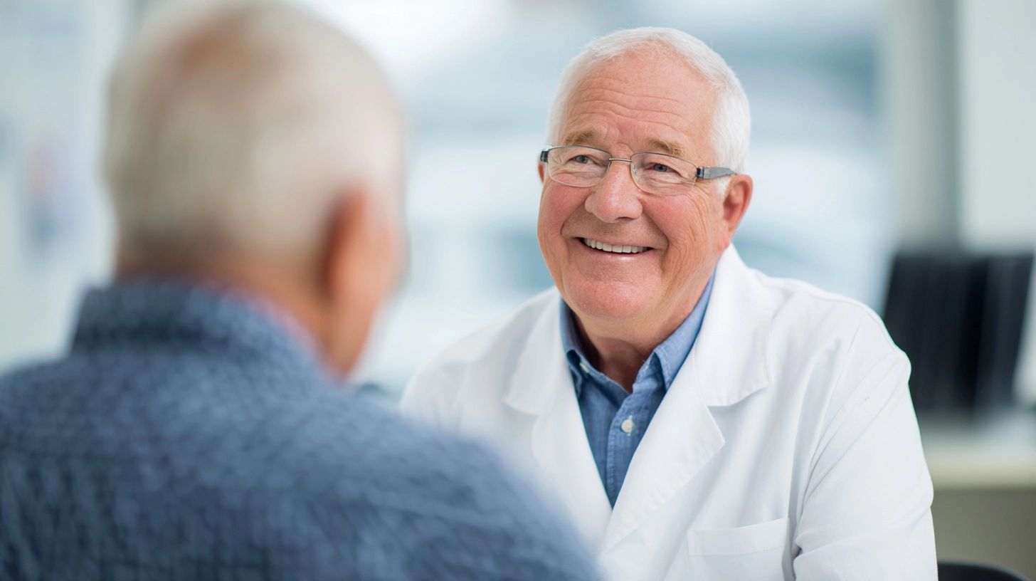 Medium shot of a doctor in a white coat sitting and talking to an elderly male patient in a bright c