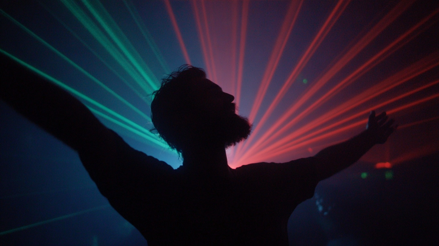 Photograph of a silluate of bearded man dancing in front of laser lights in a dark room