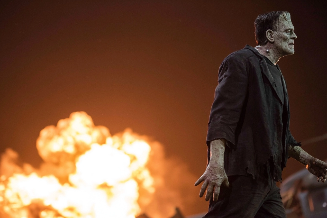 Frankenstein’s Monster. He is walking away from a crashed helicopter. The background is blazed in a