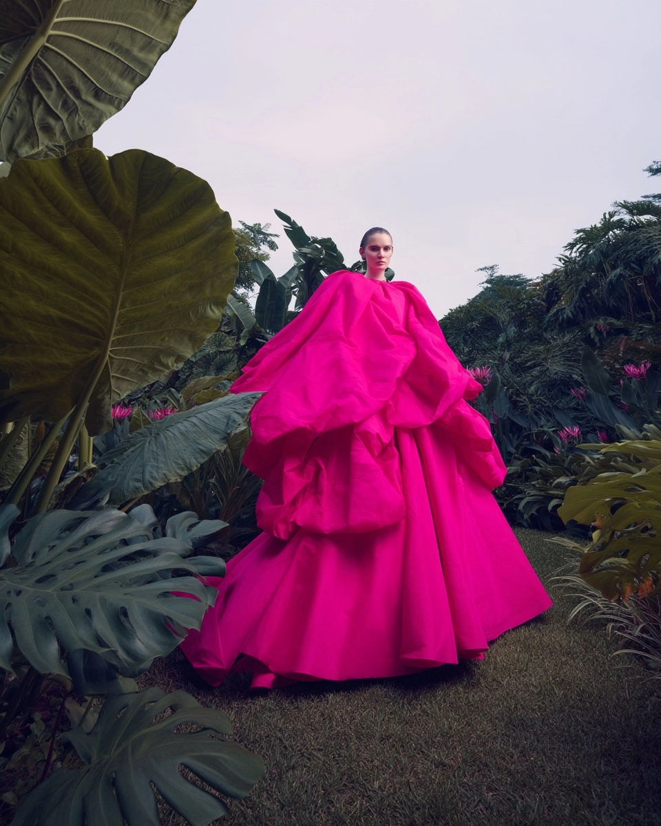 High fashion editorial image of a woman in a dramatic voluminous fuchsia couture gown, full body