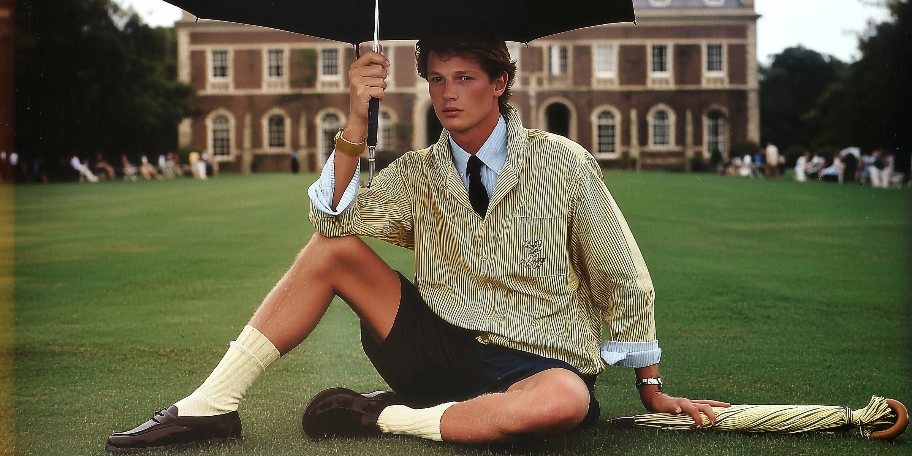 A caucasian male model in his early 20s wearing ralph lauren preppy sitting on the lawn of an old co