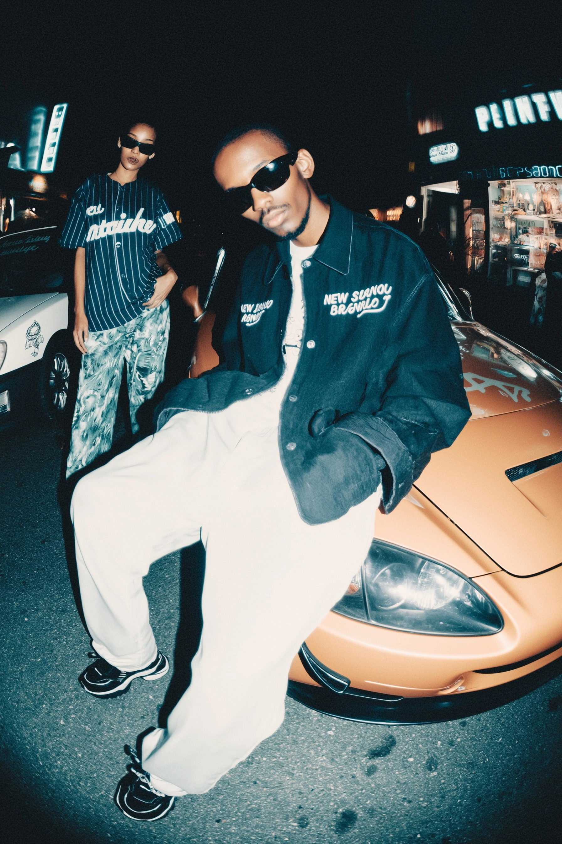 A young man in the foreground is wearing an open jacket with "new york brasileiro" embroidery