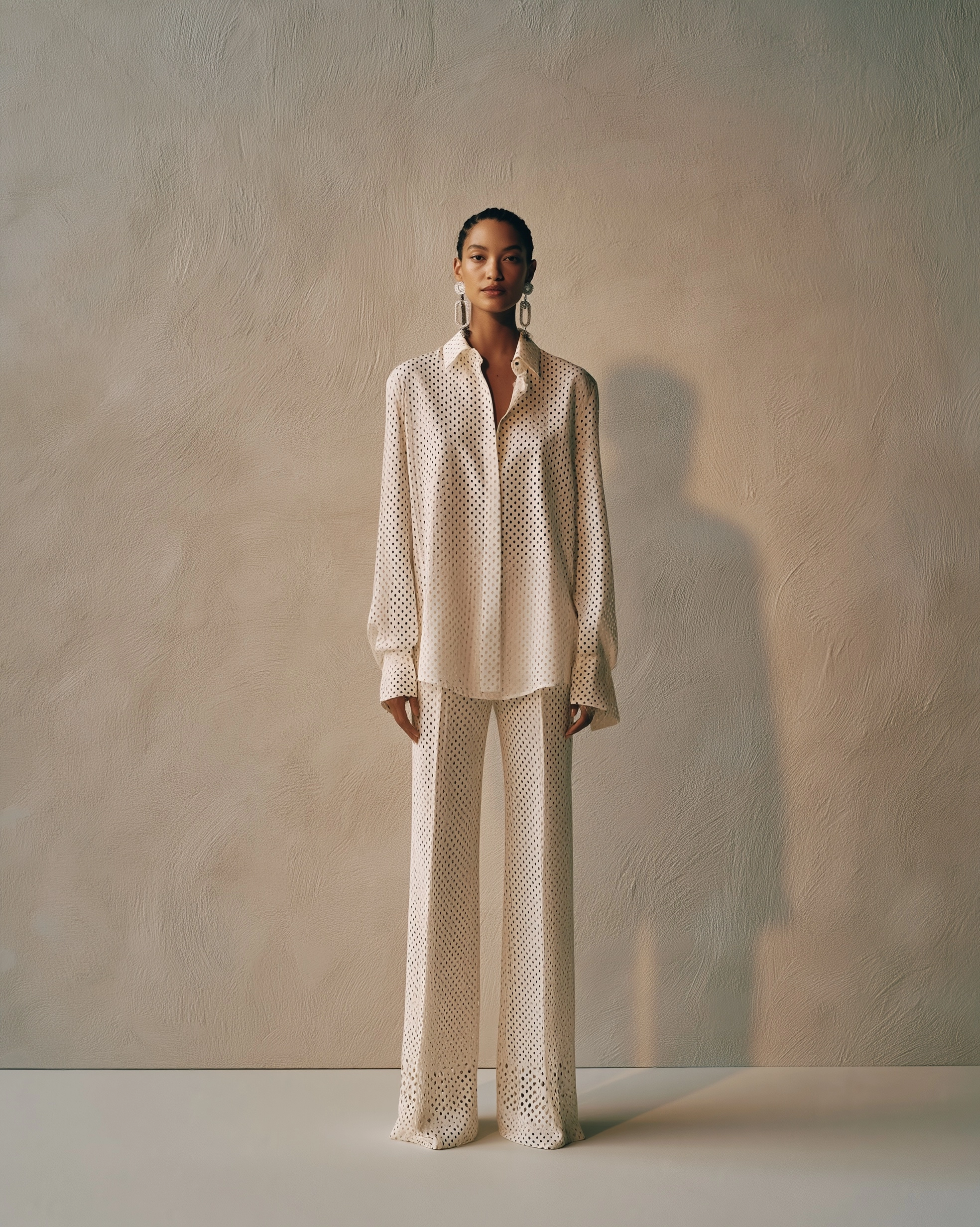 A full-body studio shot features a young beautiful top model standing against a textured