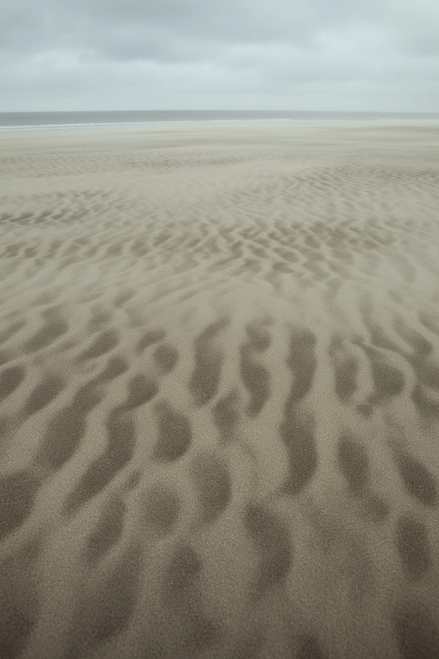 A photograph of wind-shaped sand patterns across a beach.