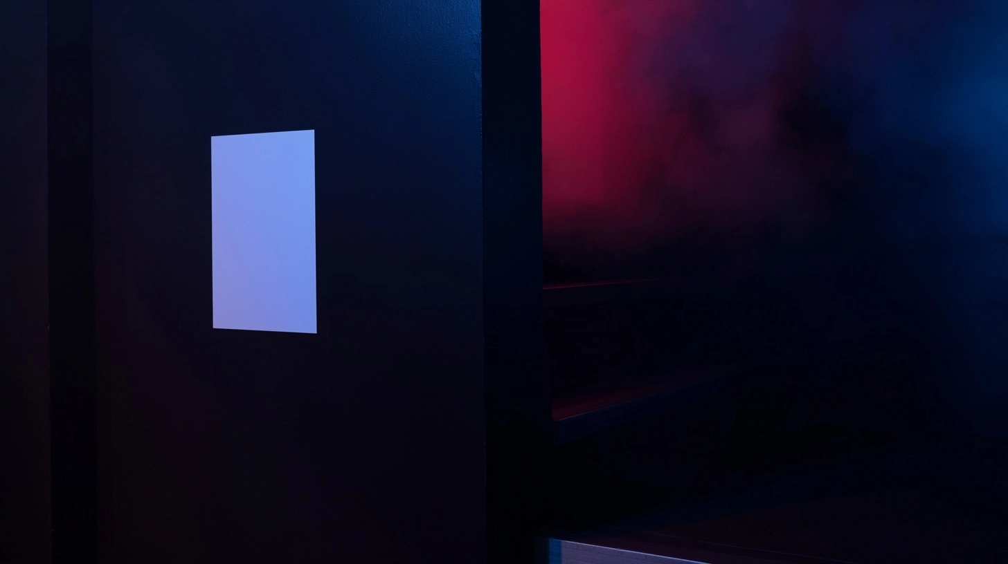 Straight-on shot of a vertical A3 white poster affixed to a black painted wall inside a nightclub. T