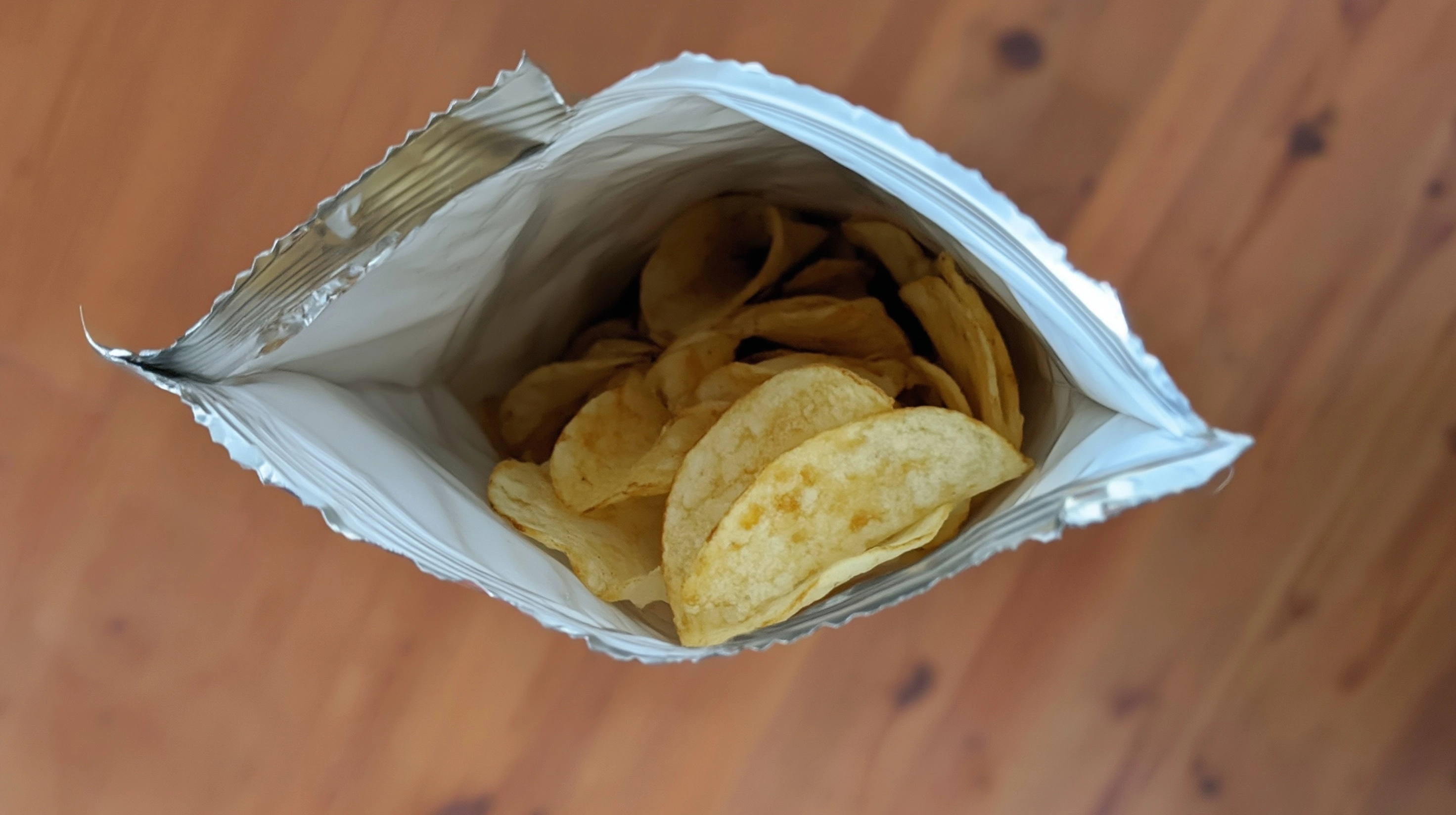 A snack bag with a hole in it; the opening is facing the ceiling.