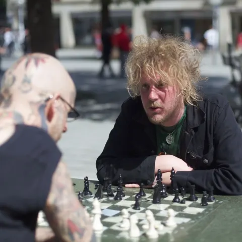 Gay Hipster antifa playing outdoor chess in Munich. Colored photograph
