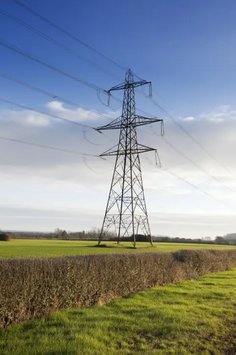 A UK electric pylon in the countryside. Focus on a single pylon. To be used in a leafet