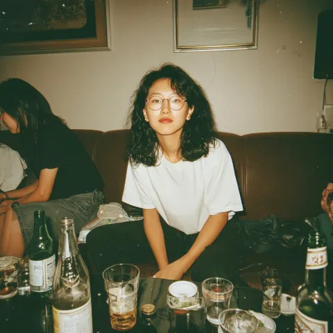 A candid flash photograph of an awkward nerdy Asian woman in her 20s with medium-length black curly