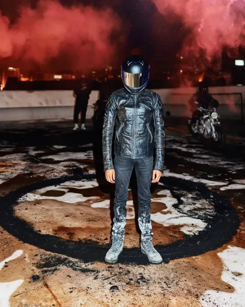 Underground rider ritual on a rooftop at night, thick black burnout circle scorched into wet concret