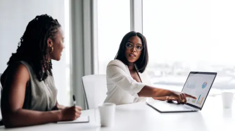 Two white professionals sitting at a clean white desk in a modern office