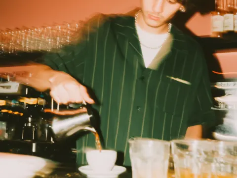 A young man making coffee the old way, very close-up, interior, inside of a Berlin based cafe