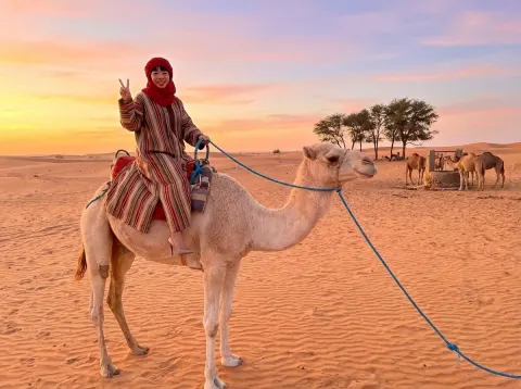 Woman Riding Camel At Sunset