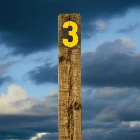 Weathered Post Crowned With a Yellow Three