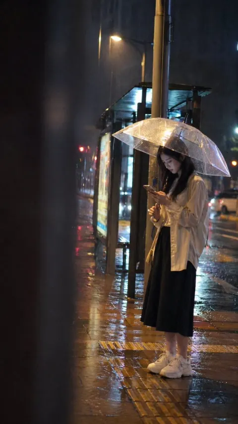 Girl Waiting at a Bus Stop on a Rainy Night