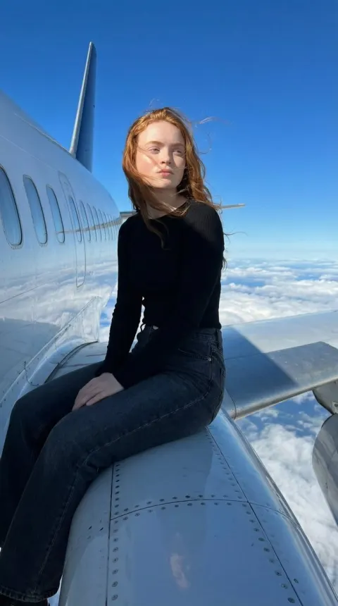 Woman Sitting On Airplane Above Clouds