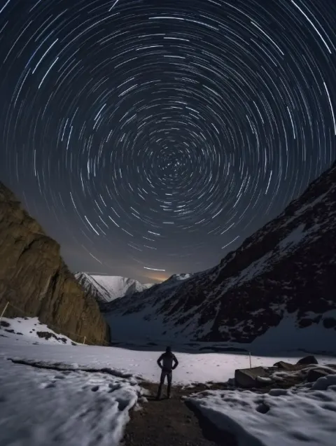 Circular Star Trails Over Man With Searchlight