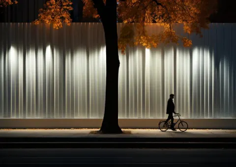 Cyclist on Minimalist Path Along White LED Striped Fence