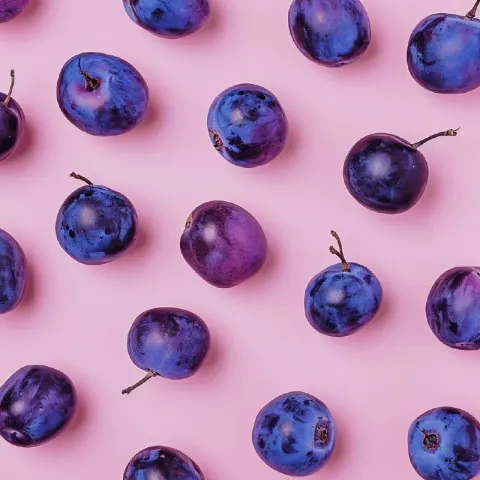 Minimalist Flat Lay of Purple Plums on Pastel Pink