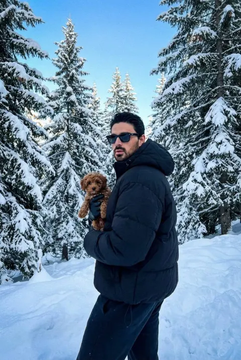 Stylish Man Holds Puppy In Snow