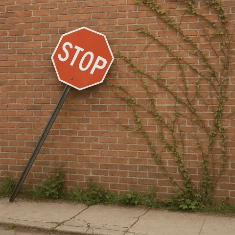 Leaning Stop Sign Stands near a Red Brick Wall