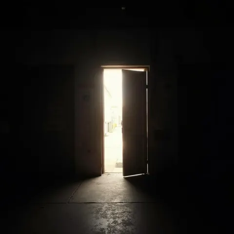 Brightly Lit Door Glowing Through Urban Darkness