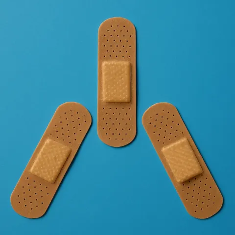 Three Brown Adhesive Bandages Arranged in a Triangular Formation