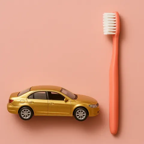 Coral-colored Toothbrush Positioned Next to a Golden Car That’s