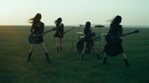 A cinematic wide shot of a four-member Chinese girl rock band performing on a vast empty grassland