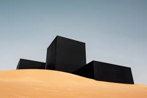 A brutalist building composed essentially of giant black balloons in a desert (like dune film)