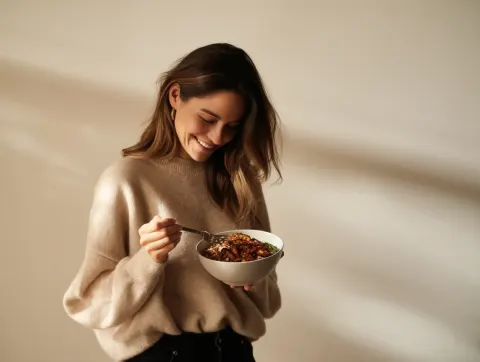 A woman in her late thirties, wearing an elegant beige sweater and black jeans