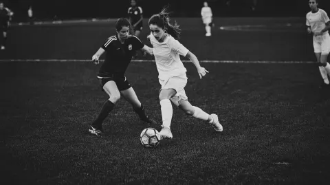 A dynamic black and white photo of a young soccer player photographed as if in a real game as they d