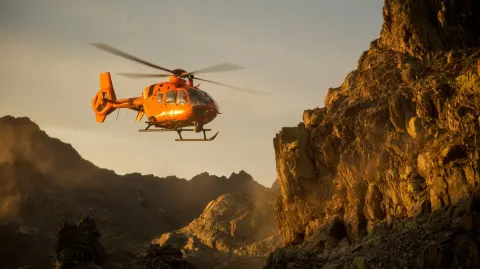 Locked two meters behind the EC135's tail boom, the orange rescue bird banks hard left around a gran