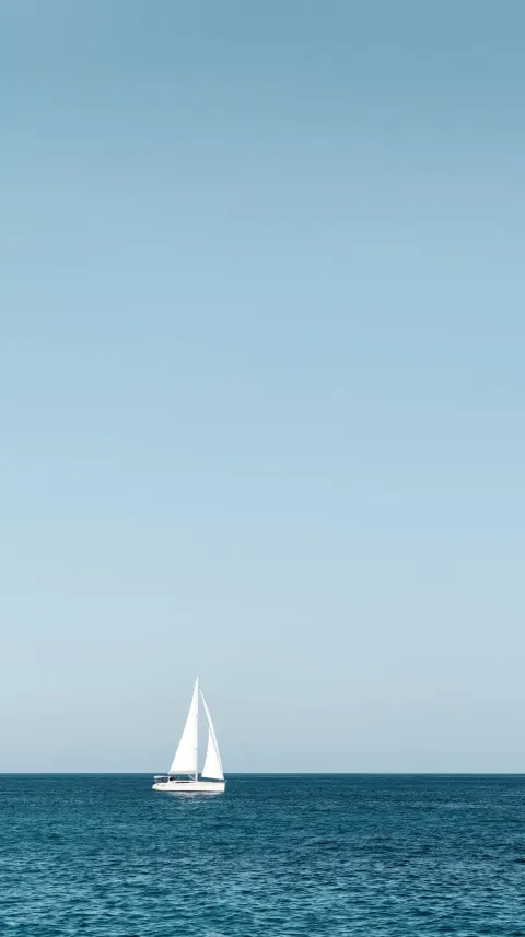 A minimalist travel photograph of a sailboat, styled after the sleek white sailboat with two triangu