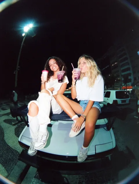 Fisheye 1990s quality shot of two Brazilian women in street clothing sitting on the wing of their JD