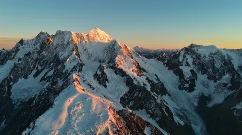 A cinematic movie shot, wide shot of the a steep snow mountains and glaciers. The sky is clear with