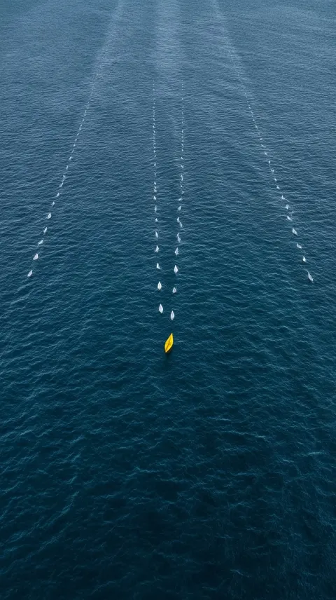 Wide medium shot from slightly above of the yellow paper boat in the ocean