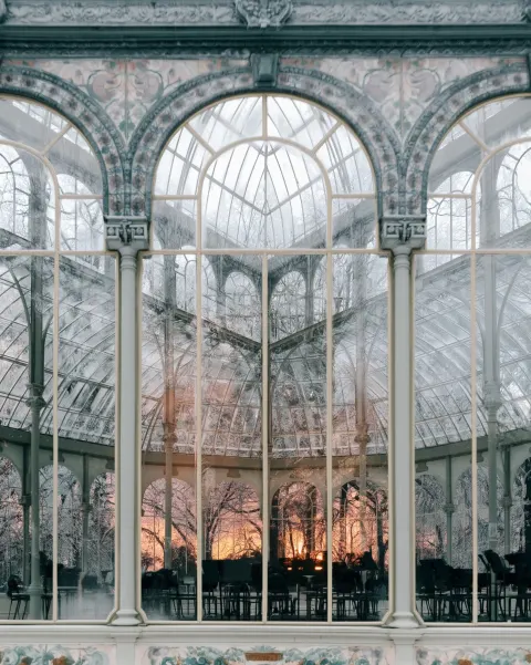 A glass conservatory bandstand in winter, its ironwork traced with frost while the empty music stand