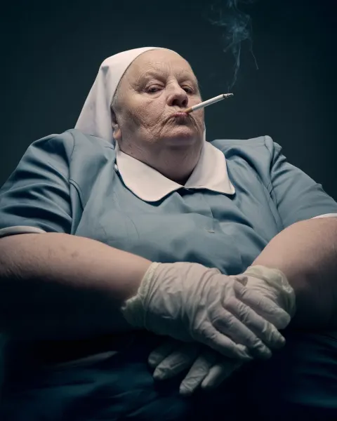Elderly large unpleasant nurse in uniform smoking a cigarette
