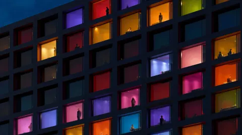 A modern business building facade with vibrant multicolored windows at night