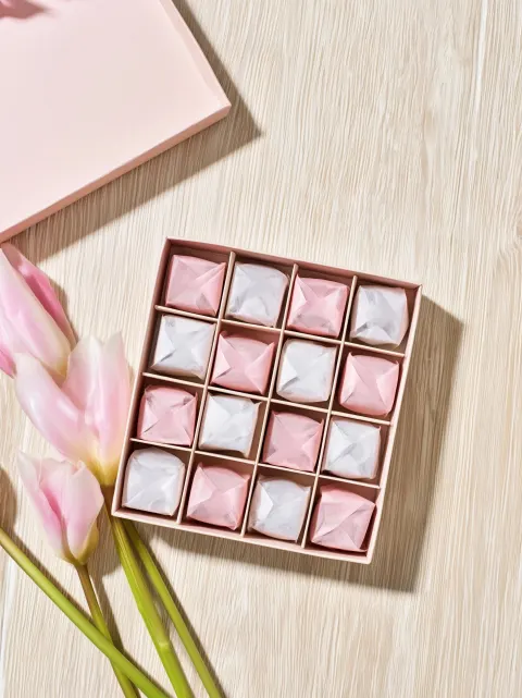 A beautiful open gift box with 12 small square chocolates inside