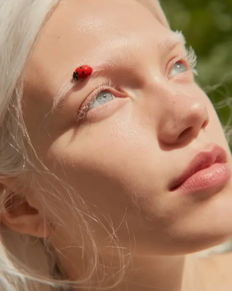 Ultra-realistic macro beauty portrait of a young woman’s eye and temple captured in warm natural sun